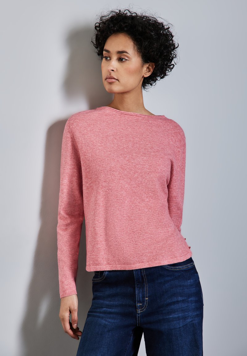Ljust rosa, långärmad tröja med rund hals och något cropped design, kombinerad med mörkblå jeans. Mjuk textur och avslappnad passform.
