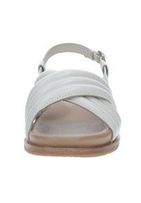 Sandal in pelle bianca con cinturini incrociati, cinturino alla caviglia regolabile e soletta imbottita color beige. Suola piatta con una leggera finitura traslucida.