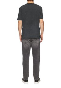 Zwarte korte mouwen t-shirt met een textuur afwerking, gecombineerd met grijze slim-fit jeans met achterzakken en een lichte vervaging.