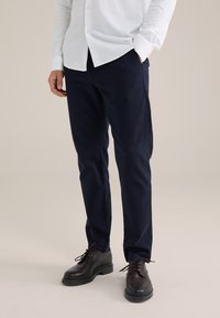 Jūras kareivju bikses izgatavotas no kokvilnas, šaura piegriezuma dizains, plakana priekšdaļa, ar sānu kabatām. Apvienotas ar melnām ādas kurpēm un baltu krekla ar pogām.