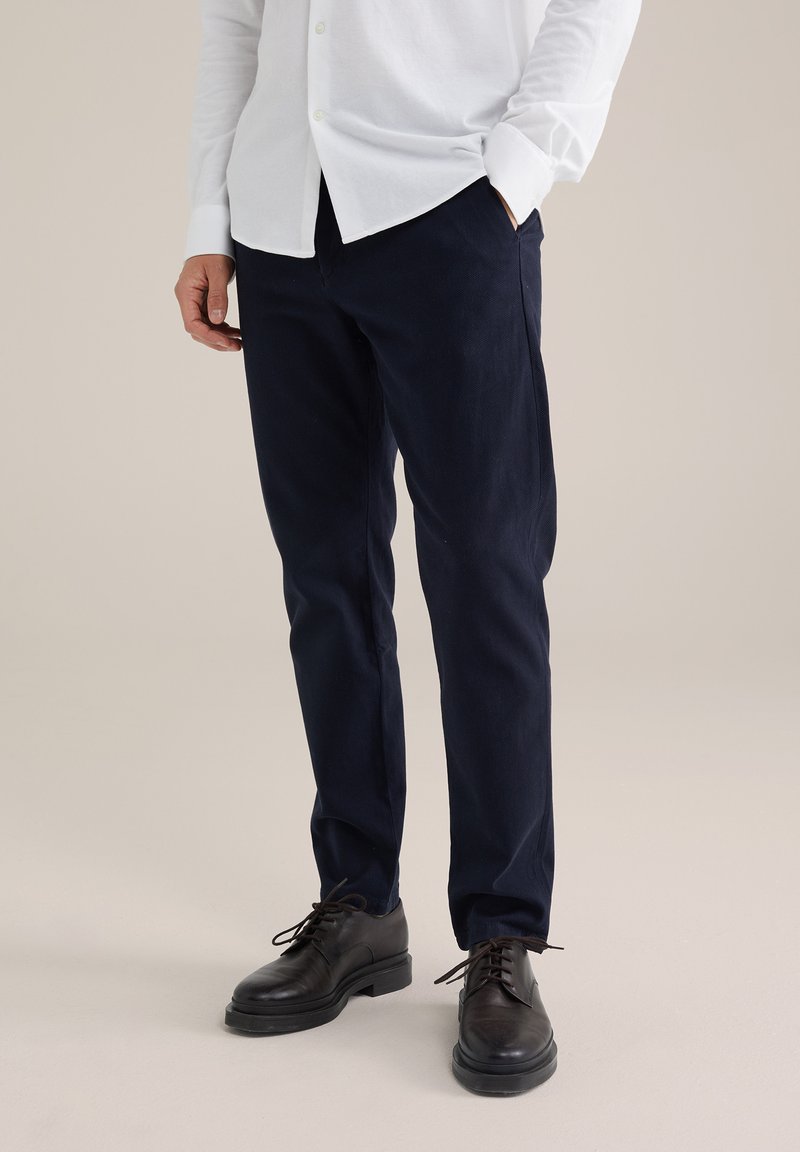 Jūras kareivju bikses izgatavotas no kokvilnas, šaura piegriezuma dizains, plakana priekšdaļa, ar sānu kabatām. Apvienotas ar melnām ādas kurpēm un baltu krekla ar pogām.