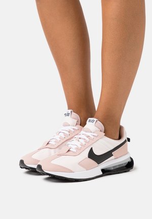 Nike sneakers har en pink og hvid mesh-overdel med sorte accenter, en rund tå, snørelukning og en synlig luftdæmpningsenhed.