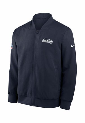 Giacca bomber blu navy in tessuto leggero, con logo Seahawks sul petto e Swoosh Nike sulla manica. Chiusura frontale con cerniera.