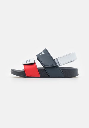 Børns sandal med åbne tæer med røde, marineblå og hvide justerbare stropper og tekstureret sort sål, designet til afslappet brug.
