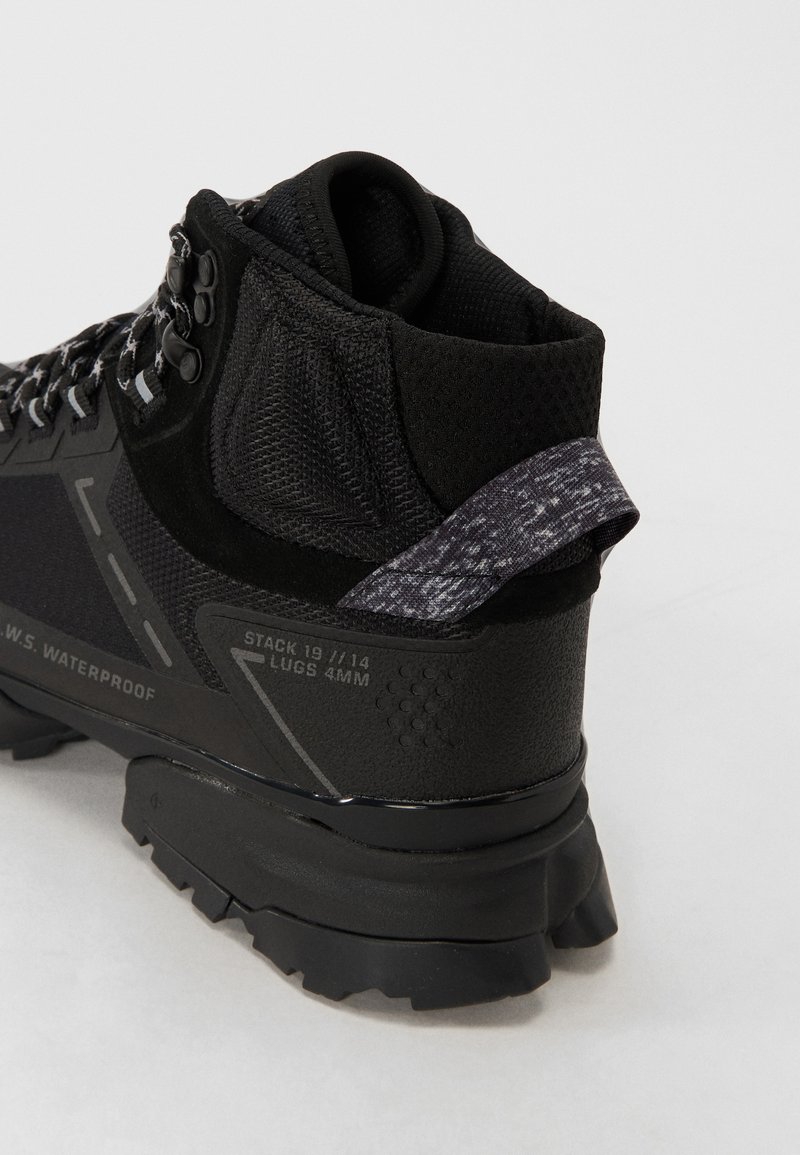 Czarne wodoodporne buty trekkingowe z teksturowaną cholewką, wzmocnionym piętą, odblaskowymi akcentami i wytrzymałą gumową podeszwą.