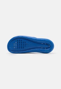 Blue rubber shoe sole featuring circular and hexagonal patterns, textured edges, and ventilation holes for breathability.