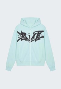 Sweat à capuche bleu clair zippé avec capuche, poches avant, et texte audacieux en style graffiti noir sur la poitrine.