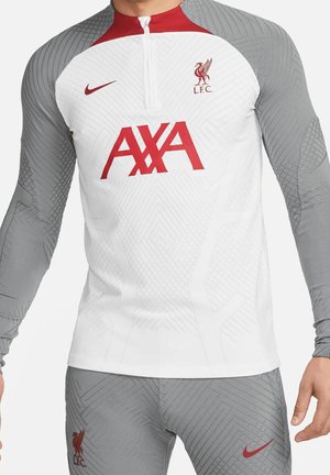 Haut d'entraînement du Liverpool FC en blanc et gris avec logo AXA rouge, swoosh Nike et écusson du club sur la poitrine, porté par une personne.