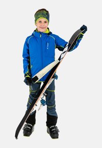 Veste de ski bleue avec des accents verts, pantalon de ski gris et bottes de ski noires. L'enfant tient des skis avec une prise noire et une base blanche. Bandeau coloré.