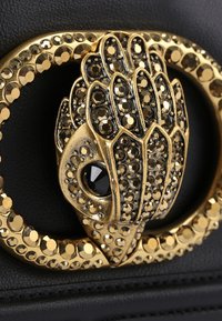 Borsa a tracolla in pelle nera con una fibbia decorativa dorata a forma di mano, adornata con strass neri e dorati.