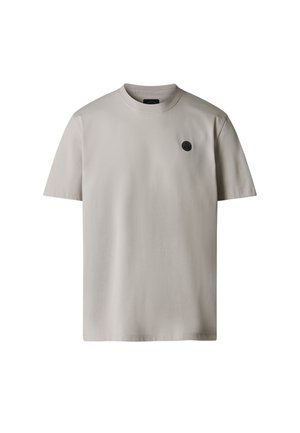 T-shirt beige chiaro a maniche corte con scollo rotondo, con un piccolo logo nero rotondo sul lato sinistro del petto, su sfondo bianco.