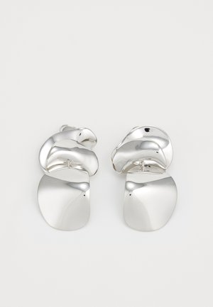 Silver metal earrings featuring a sculptural, twisted design with smooth and shiny surfaces, complemented by flat, rounded shapes.