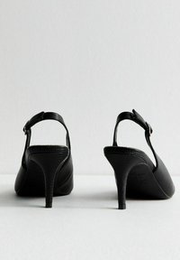 Scarpe con tacco a slingback nere con finitura testurizzata, punta affusolata e design con tacco sottile. Presentano una cinturino con fibbia per una vestibilità sicura.