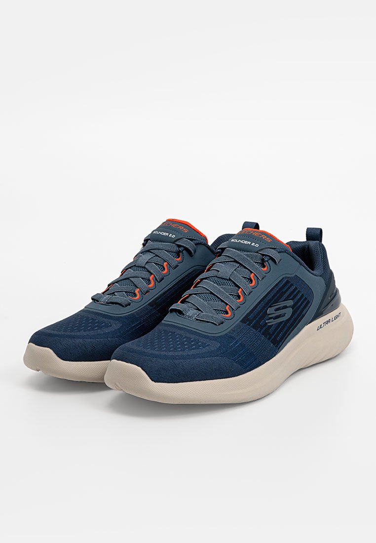 Zapatillas deportivas de color navy con empeines de tela texturizada, detalles en naranja en los cordones y la lengua, y una suela de goma clara.