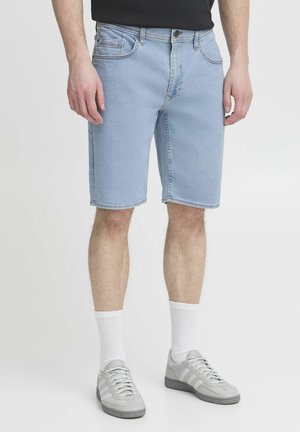 Ljusblå denimshorts med rak passform, fem fickor och kontrasterande sömmar. Matchas med grå sneakers och vita strumpor.