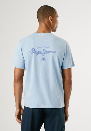 Helleblaue Baumwoll-T-Shirt mit Vintage-Waschung. Das Shirt hat ein großes blaues Logo auf dem Rücken, kurze Ärmel und einen runden Ausschnitt.