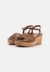 Sandali intrecciati marroni con tacco in sughero, dotati di una parte superiore intrecciata, design open toe e cinturino alla caviglia regolabile.