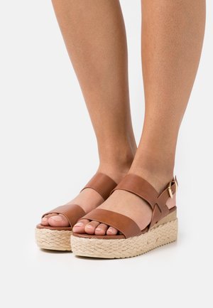 Bruine leren espadrille sandalen met twee brede banden, open neus en een geweven jute platformzool. Voorzien van een gesp op de hielband.