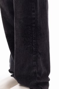 Dark denim pants with a relaxed fit, featuring subtle embroidery on the lower leg and contrasting stitching along the seams.