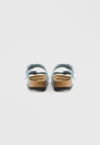 Μπλε σανδάλια με δύο λουριά, πάτο από φελλό και μαύρη λαστιχένια σόλα. Διαθέτουν ρυθμιζόμενες αγκράφες και απαλό υλικό που μοιάζει με σουέντ.