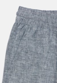 Pantaloni corti grigi in tessuto intrecciato con una vita elasticizzata, caratterizzati da una consistenza morbida e tasche laterali. I dettagli di cucitura arricchiscono il design.