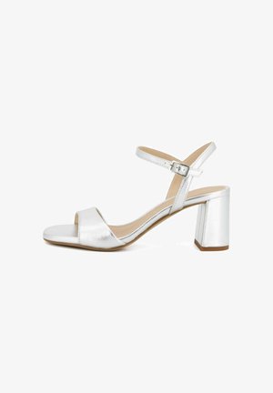 Sandalo argentato con tacco aperto, cinturino alla caviglia con fibbia, tacco a blocco e finitura liscia su sfondo bianco.
