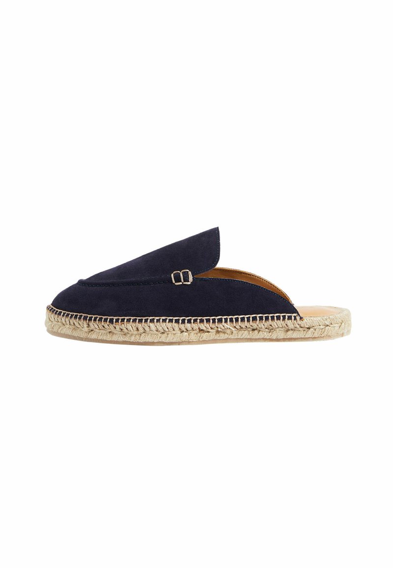 Espadrilla de ante azul marino con abertura en la parte trasera, que cuenta con una suela de yute tejido y un detalle decorativo de hebilla en la parte superior. Diseño plano y minimalista.
