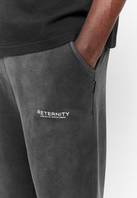 Gray sweatpants with a soft texture, featuring a side pocket and a white logo "RETENRITY CREATIVE DEPARTMENT" on the left thigh.
