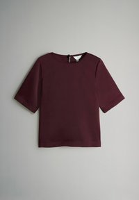 Burgunderfarvet kortærmet top med rund halsudskæring og en nøglehulslukning i ryggen. Glat tekstur og minimalistisk design med rene linjer.