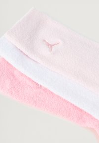 Set aus drei weichen Fleece-Stirnbändern in Hellrosa, Weiß und Dunkelrosa, mit einem kleinen gestickten Logo auf einem der Bänder.