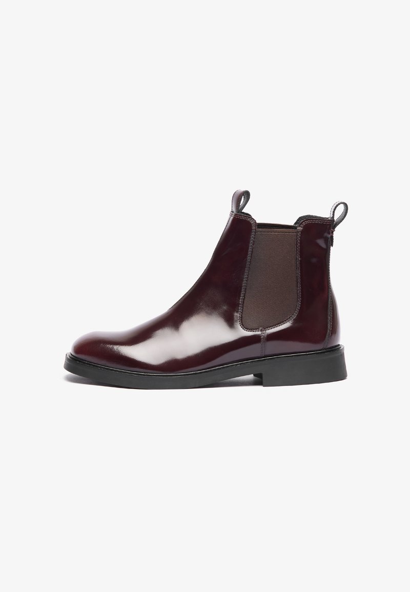 Botte Chelsea en cuir brun foncé brillant avec des panneaux élastiques sur les côtés, des languettes à l'avant et à l'arrière, et une semelle en caoutchouc noir.