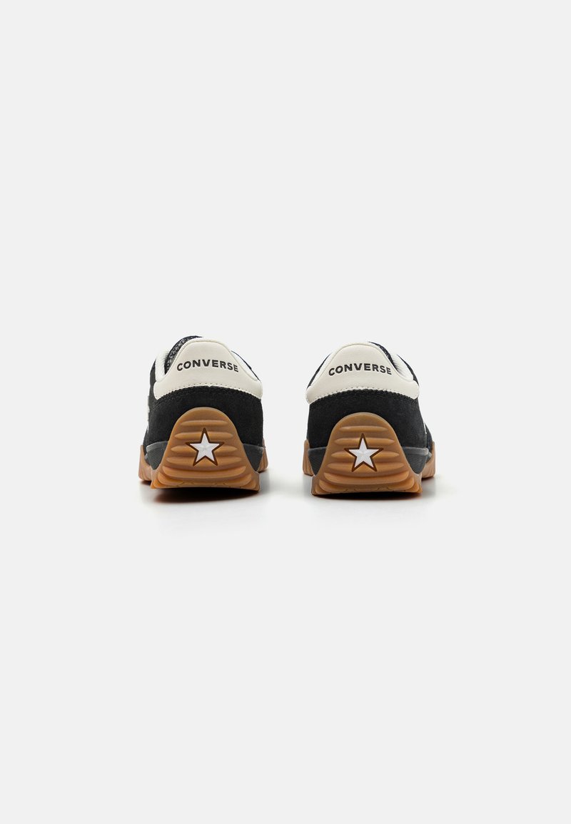 Zapatillas de ante negras con detalles en blanco, que cuentan con una suela de goma con un logo de estrella, talón acolchado y una suela exterior de goma de contraste.