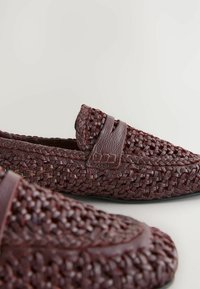 Mocassins en cuir tressé bordeaux avec une finition texturée, dotés d'une large bande et d'un discret logo sur le côté. Conçus pour un enfilage facile.