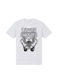 Bílá bavlněná trička se černým grafickým designem s textem "Lynyrd Skynyrd", orlem a dvěma elektrickými kytarami.