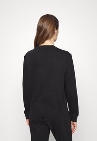 Svart sweatshirt med rundad halsringning och långa ärmar. Slät yta och ribbade muddar. Minimalistisk design, inga synliga logotyper eller mönster.