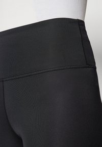 Leggings negros de tiro alto fabricados con un material suave y elástico, con una cintura plana y costuras mínimas para un aspecto aerodinámico.