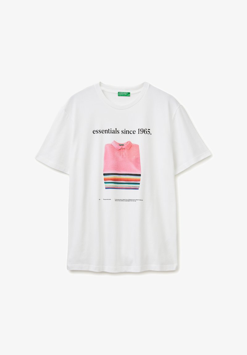 Wit T-shirt met een afbeelding van een gevouwen roze poloshirt en kleurrijke strepen, met daarboven de tekst "essentials since 1965."