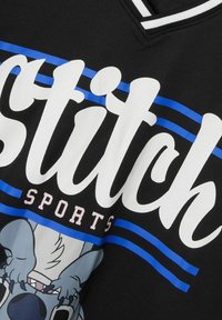 Maillot de sport noir avec un grand texte "Stitch" en blanc, des rayures bleues et une illustration d'un personnage de dessin animé en bas.