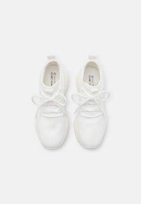 Białe sneakersy z siateczki z teksturowanymi panelami, płaskimi sznurówkami i wyściółką. Posiadają pętelkę z tyłu dla łatwego zakładania. Materiał wegański.