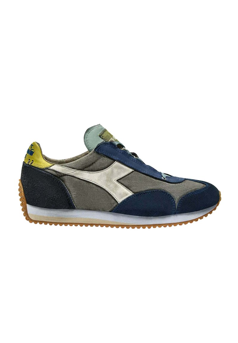 Zapatilla con parte superior de materiales mixtos en azul marino, gris y amarillo. Presenta un logotipo blanco, cordones azules y una suela de goma texturizada.