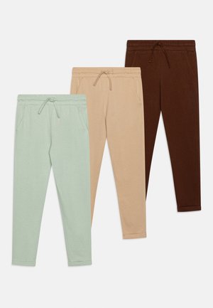 Set van drie casual joggerbroeken met elastische taillebanden en trekkoorden in mintgroen, beige en donkerbruin, plat gelegd op een witte achtergrond.