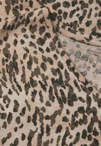 Beiger Stoff mit einem Leopardenmuster in Dunkelgrün und Schwarz. Die Textur ist weich und leicht erhaben, mit einem runden Ausschnitt.
