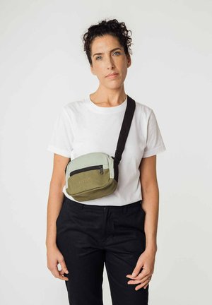 Grüne und hellgrüne Umhängetasche mit einem Reißverschlussfach, aus Stoff gefertigt, verfügt über einen schwarzen Schulterriemen und ein geprägtes Logo.