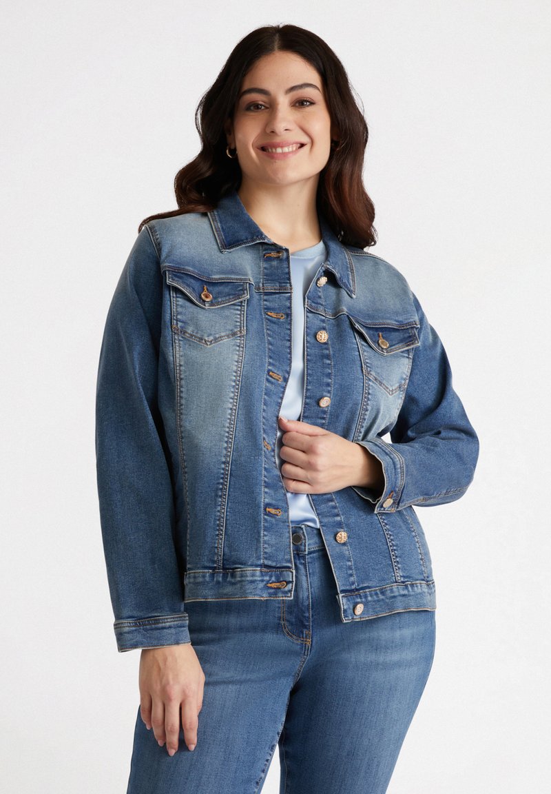 Veste en denim avec un dégradé bleu clair à bleu foncé, dotée de poches, de boutons en bronze et de manches longues. Texture douce, design classique.