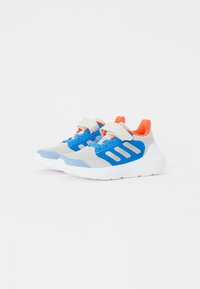 Baskets grises et bleues avec une tige en mesh, une sangle velcro et des accents orange fluorescents. Semelle blanche, forme élégante et trois rayures bleues sur le côté.