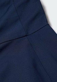 Tissu bleu marine à la texture lisse, avec un détail de couture courant verticalement le long d'un côté. Design élégant et ajusté.