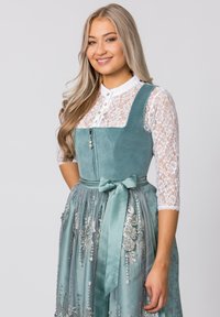 A green suede bodice dress with a white lace blouse, featuring a cinched waist, satin bow, and embroidered silver floral designs on the skirt.