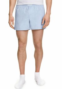 Boxer en coton bleu clair avec une taille élastique, comportant un seul bouton à l'avant et une texture lisse. Porté avec des chaussettes blanches.
