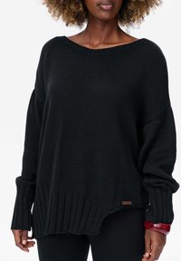 Pull noir surdimensionné avec un tricot texturé, col large et ourlet côtelé. Il présente des manches longues et une étiquette de marque subtile sur la couture latérale.