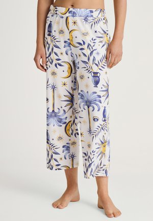 Witte, geprinte broeken met blauwe en gele illustraties van manen, zonnen, ogen en planten. Losse pasvorm, elastische taille en cropped lengte.